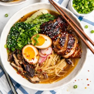 Bowl of homemade chicken ramen garnished with green onions and egg.